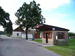 Autobusová zastávka a stavení č. p. 1 při silnici II/317 na kraji vesnice