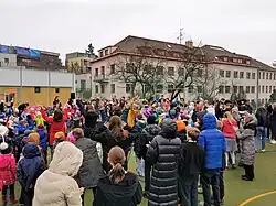 Budova školy svatého Augustina s hřištěm zaplněným žáky, pedagogy a rodiči během oslav thanksgiving 24. listopadu 2022.