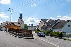 Střed obce s kostelem sv. Vavřince, roubenkou a základní školou