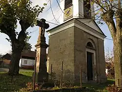 krucifix na podstavci s reliéfy vedle zvoničk