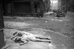 Těla zabitých žen v osvobozeném budapešťském ghettu. Ulice Šándora Petöfiho (Petőfi Sándor utca). Vlevo ulička Pilvaks (Pilvax köz). Pohled směrem k náměstí Františkánů (Ferenciek tere). Více než 220 tisíc budapešťských Židů bylo za fašistického režimu přemístěno do ghetta.