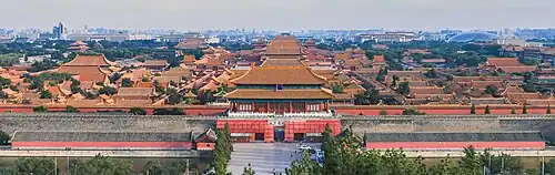 Fotografie, pohled z nadhledu na zakázané město, za hradbami jsou vidět řdy červených střech budov v pozadí se strácející v mlze.