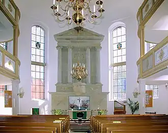 Uprostřed je šedavý oltář se čtyřmi sloupy a trojúhelníkovým štítem, v dolní části oltáře je abstraktní oltářní obraz, před oltářem černá křtitelnice, ze stropu visí křišťálový lustr, vedle oltáře jsou vysoká okna, po stranách dvoupatrové galerie, v přední části hnědé lavice