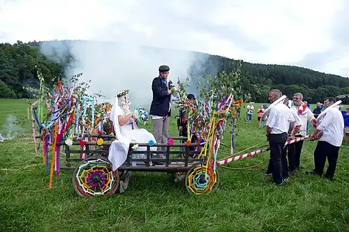 Novomanželé nasedli do přistaveného žebřiňáku a za zpěvu děvčat odjíždějí v průvodu ostatních svatebčanů do hospody