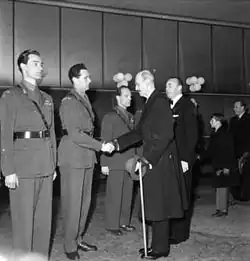 Král Haakon VII. podává ruku Poulssonovi a dalším odbojářům na slavnostní norské premiéře filmu Boj o těžkou vodu (1948)