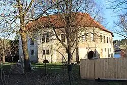 Celkový pohled z návsi na severní a západní křídlo s bránou.