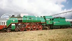 Pohled z levého boku na zeleně zbarvenou stojící parní lokomotivu