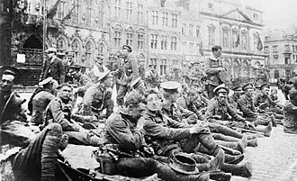 Britští vojáci z regimentu Royal Fusiliers odpočívají na náměstí v Monsu před bitvou. Royal Fusiliers čelili nejtěžším bojům v bitvě a první z války získali Viktoriin kříž.