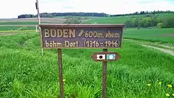 Pohled na místo zaniklé osady (lesík vpravo v údolí za tabulí)