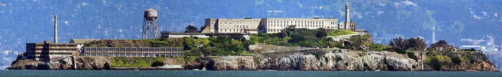 Alcatraz v Sanfranciském zálivu z východu; na pevnině vpravo je zvonice Sather Tower s kampusem Kalifornské univerzity v Berkeley