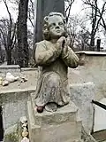 Soška andělíčka na vrcholu náhrobku (detail)