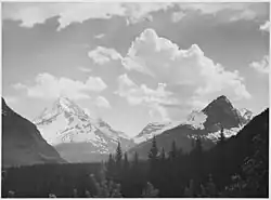 Pohled přes les na hory a mraky, Národní park Glacier, Montana, 1941