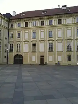 Slepá okna prozrazují zachovalou hmotu románské Bílé věže (v ose dveří); vlevo od ní prezidentský průjezd, ve středověku západní vstup do hradu, který věž střežila