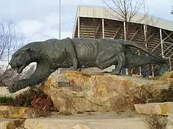 Bronzová socha na žulovém kameni zobrazující plížící se šelmu s nataženou pravou packou dopředu, podobající se pumě