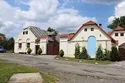 Objekt statku tvoří dvě souběžně stojící zděné přízemní budovy přivrácené štíty. Mezi nimi je zděná zeď plotu, v níž je umístěna dřevěná brána.