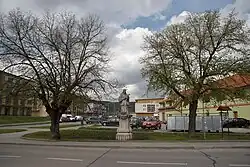 Socha sv. Jana Nepomuckého s novou výstavbou v pozadí