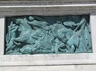 Fotografie bronzového reliéfu ztvárňující bitvu.