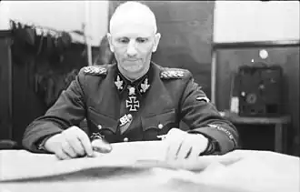 Gille ještě v hodnosti SS-Gruppenführera během jara roku 1944 v Sovětském svazu. U jeho krku můžeme vidět vysoce cenněný rytířský kříž železného kříže s dubovými ratolestmi a meči.