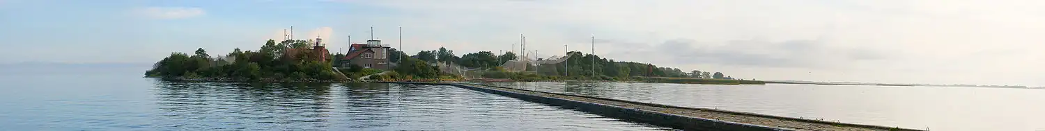 Mys Ventės ragas: pohled od mola, Delta Němenu je vpravo; v popředí ornitologická stanice/muzeum, od ní vlevo Ventėský maják, vpravo sítě k odchytu tažných ptáků ke kroužkování. Zářijové jitro. panoráma