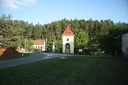 Střed obce s kaplí sv. Cyrila a Metoděje, křížem a památníkem vystěhování občanů