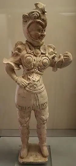 Fotografie štíhlé terakotové sošky strážce v přiléhavém zdobném brnění, béžové barvy