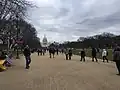Lidé přicházejí parkem National Mall ke Kapitolu