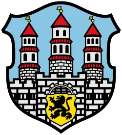 Barevná reprodukce městského znaku s motivem hradby a tří věží, v dolní části je štít se lvem