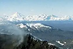Masív vulkánu Dzenzur sa nachází přibližně v středu obrázku. V pozadí (vlevo) Korjacká sopka a v popředí kráter Karymské sopky