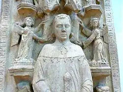 Fotografie náhrobku s reliéfem ležícího muže v rouchu, který v rukách drží meč. Ruce s mečem má položené na břichu.