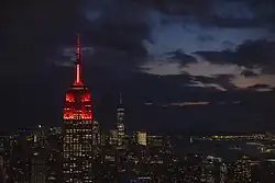 Empire State Building při západu slunce. Vrchol a několik pater pod ním je osvětleno červeně.