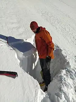 Na fotografii je osoba stojící pod izolovaným blokem sněhu o rozměrech 90 cm horizontálně a 30 cm do svahu. Je patrná uvolněná sněhová deska ve vrchní části tohoto bloku.