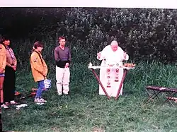 Bratr Kukůskůs slouží polní mši na táboře dobříšských oddílů (zmínka o tomto táboře je v knize Humor v církvi dovolen)