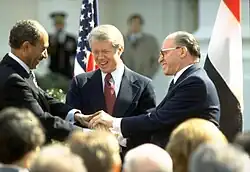 Tři muži v oblecích si potřásají rukou