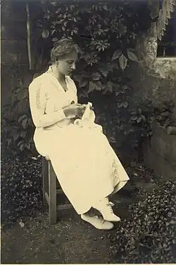 Žena vyšívá v zahradě, 1915–1925