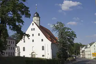 Barevná fotografie s pohledem na štít budovy na obdélníkovém půdoryse se sanktusníkem