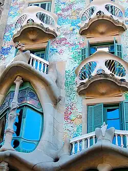 Barevná secesní fasáda budovy Casa Batlló v Barceloně s organickými tvary, pestrými mozaikami a neobvyklými zakřivenými liniemi typickými pro Gaudího styl