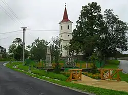 Hucín – kostel, v popředí památník obětem světových válek a pomník Sándora Petőfiho