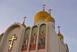 Zlatý kříž a ikony světců na průčelí katedrály