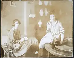 Group portrait of Joan and Lin seated in their shop, asi 1917-1925