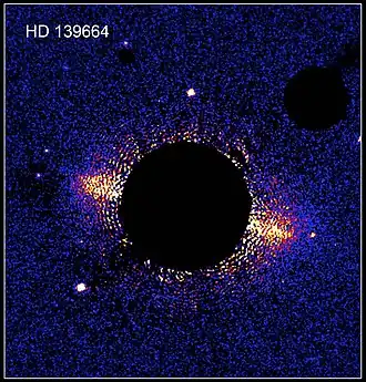 Cirkumstelární disk kolem hvězdy HD 139664 na snímku Hubblova vesmírného dalekohledu. Hvězda samotná je skryta za clonou koronografu.