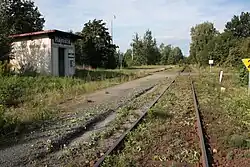 Pohled na kolejiště železniční zastávky v Hajništi. Jsou zde dvě koleje a za nimi (na snímku vlevo) stojí zděná čekárna.