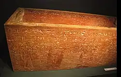 Otevřený sarkofág vystavený ve vitríně, který je popsaný hieroglyfy