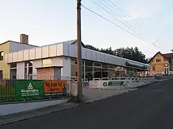 Pohled na přízemní budovu autosalonu. Před ní se nachází parkoviště k prezentaci nových vozů.