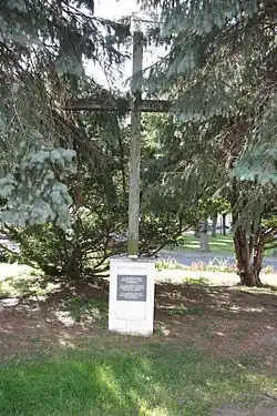 Mezi jehličnatými stromy stojí dřevěný kříž na betonovém podstavci, na němž je tabulka postupně s českým, německým a polským nápisem „Na hrobech našich zemřelých si v Pánu odpouštíme.“