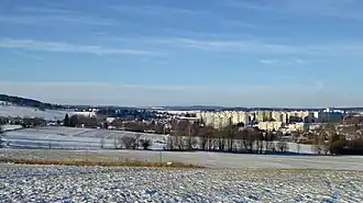 Město Hlinsko ze svahové kupy v lokalitě K Pláňavům (620 m) na severozápadním úbočí vrchu Pešava (697 m), vpravo bytové domy sídliště, vlevo starší zástavba, na obzoru vrchol Vestec (668 m) v CHKO Železné hory