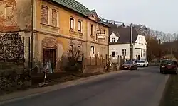 Horní Libchava čp. 21 s původní žlutou fasádou, před 2. sv. válkou majitelem Löbel Franz, po válce nájemní obecní byty, potom neobydlený, nyní soukromý dům s „Koloniálem Zdena” a sídlo dřevařské firmy, v pozadí čp. 208, stav únor 2018