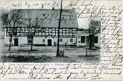 Černobílá popsaná pohlednice se snímkem hostince