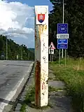 Hraniční orientační sloup v Dukelském průsmyku, zabílený, se zavěšeným slovenským znakem (v roce 2016 zrenovován do původní podoby, umístěn do muzea, místo osazeno replikou)