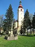 průčelí kostela s věží, v popředí sloup sv. Trojice (v současnosti přemístěný na hulínské náměstí)