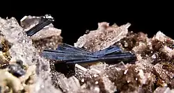 Tmavý krystal hutchinsonitu společně s barytem a auripigmentem z dolu Quiruvilca v Peru